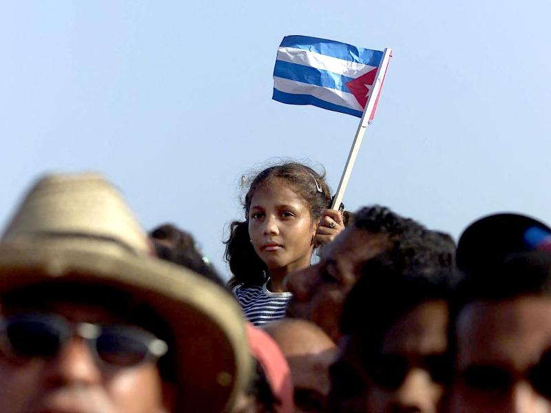 A Cuban girl wave a flag during a political meeting in the city of Manzanillo, in the province of Bayamo 01 July 2000. Photo by ADALBERTO ROQUE/AFP via Getty Images